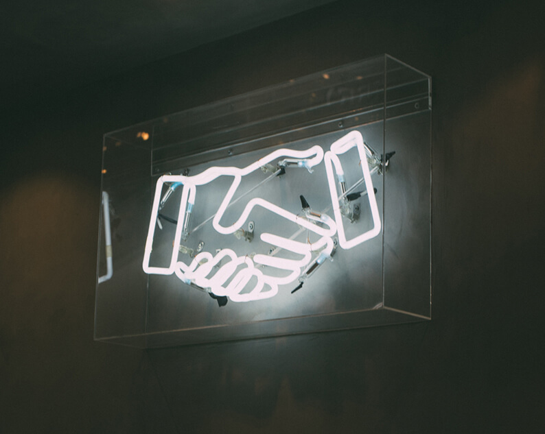 Neon sign of two hands shaking